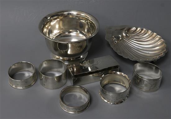A silver shell butter dish, a silver bowl, five assorted silver napkin rings and a silver stamp box.